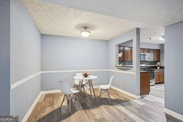 dining room with a textured ceiling, light hardwood / wood-style flooring, and sink