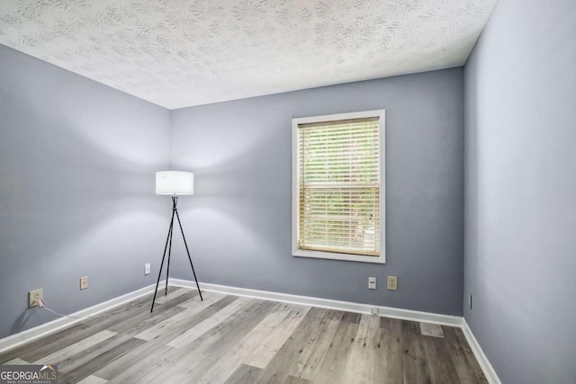 spare room featuring light wood-type flooring and a textured ceiling