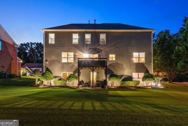 back house at dusk with a lawn and a patio area