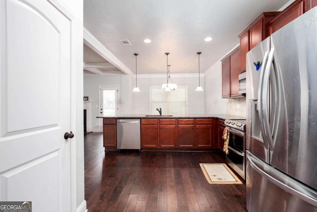 kitchen featuring tasteful backsplash, kitchen peninsula, decorative light fixtures, and appliances with stainless steel finishes