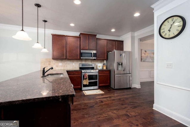 kitchen with sink, stainless steel appliances, dark hardwood / wood-style flooring, dark stone countertops, and pendant lighting