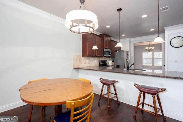 kitchen with backsplash, stainless steel appliances, dark wood-type flooring, sink, and hanging light fixtures