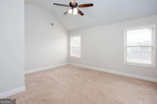 spare room with light carpet, ceiling fan, and vaulted ceiling