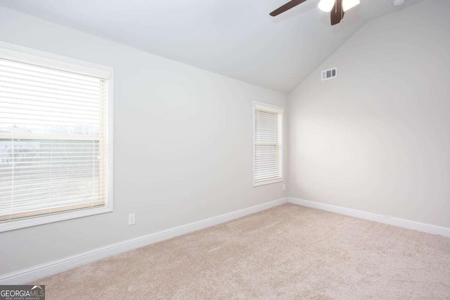 carpeted spare room featuring ceiling fan, a healthy amount of sunlight, and vaulted ceiling