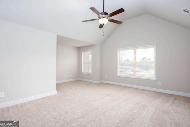 carpeted spare room featuring vaulted ceiling, ceiling fan, and a healthy amount of sunlight