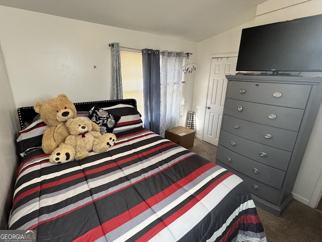 bedroom with a closet, vaulted ceiling, and dark colored carpet