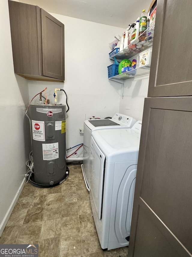 clothes washing area featuring water heater, washer and clothes dryer, and cabinets