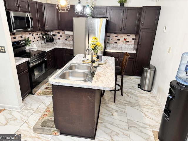 kitchen with dark brown cabinets, stainless steel appliances, a kitchen island with sink, and sink