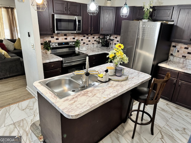 kitchen featuring pendant lighting, dark brown cabinets, stainless steel appliances, and an island with sink