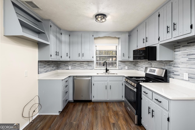 kitchen featuring appliances with stainless steel finishes, dark hardwood / wood-style flooring, gray cabinetry, a textured ceiling, and sink