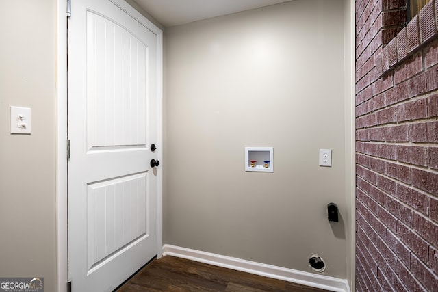 clothes washing area featuring hookup for a washing machine, dark wood-type flooring, and brick wall