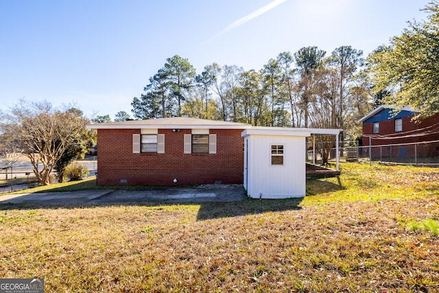 back of property featuring a yard and a storage unit