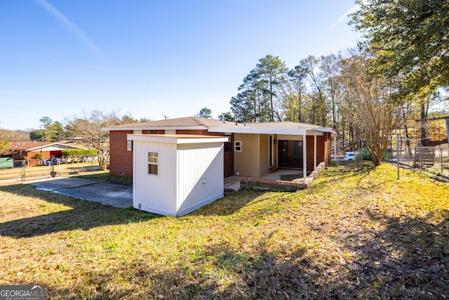 rear view of house with a lawn and a patio