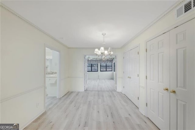 unfurnished dining area with a chandelier, light hardwood / wood-style floors, and crown molding