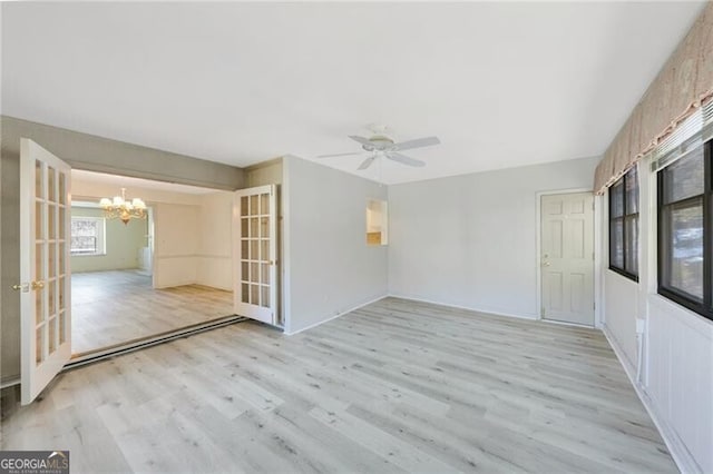 spare room with ceiling fan with notable chandelier, french doors, and light wood-type flooring