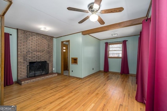 unfurnished living room featuring ceiling fan, light hardwood / wood-style floors, beam ceiling, and a fireplace