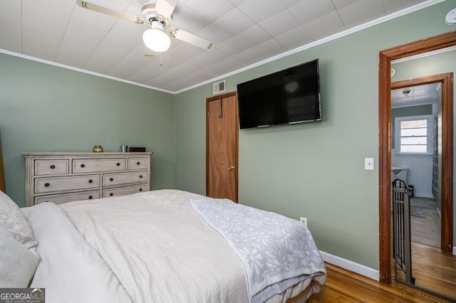 bedroom with hardwood / wood-style floors, ceiling fan, and crown molding