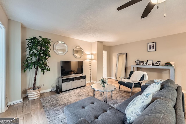 living room featuring hardwood / wood-style flooring, ceiling fan, and a textured ceiling