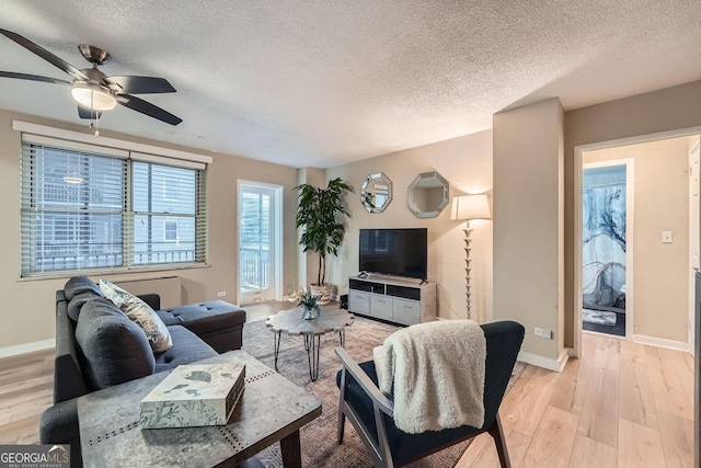 living room with ceiling fan, light hardwood / wood-style flooring, and a textured ceiling