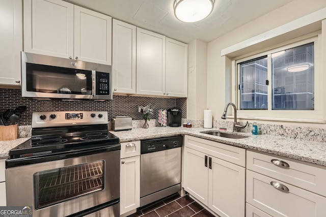 kitchen featuring sink, light stone counters, decorative backsplash, white cabinets, and appliances with stainless steel finishes