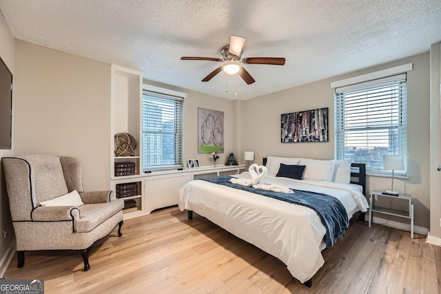 bedroom with ceiling fan, light hardwood / wood-style floors, and a textured ceiling