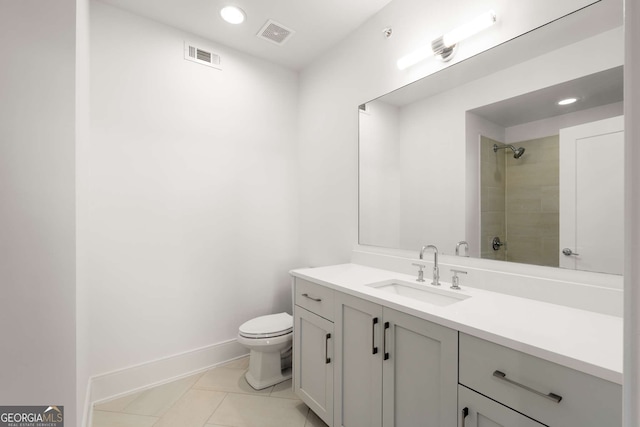 bathroom with toilet, a tile shower, tile patterned floors, and vanity