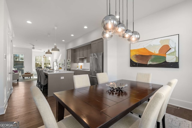 dining space with ceiling fan, dark wood-type flooring, and sink