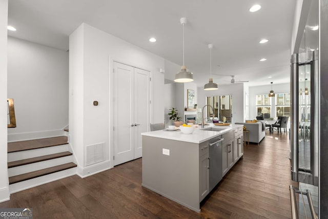 kitchen with sink, stainless steel appliances, decorative light fixtures, ceiling fan, and a kitchen island with sink