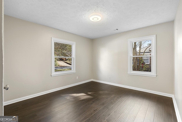 spare room featuring a textured ceiling and dark hardwood / wood-style floors