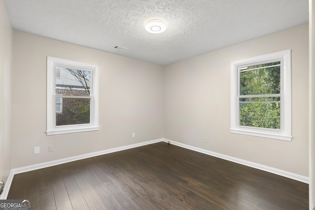 spare room featuring a textured ceiling, dark hardwood / wood-style flooring, and plenty of natural light