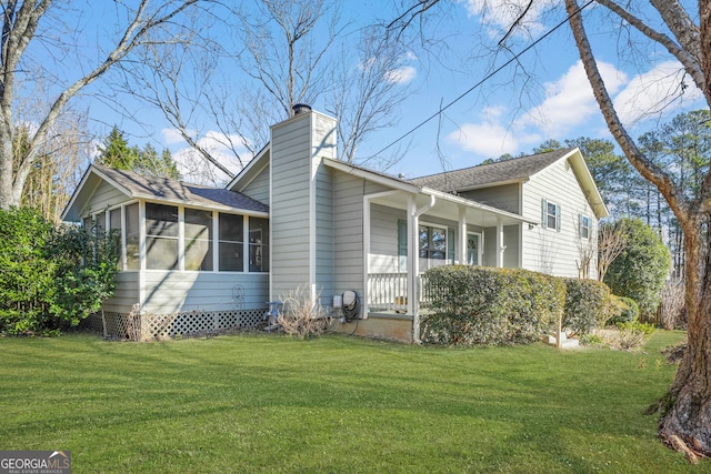 view of side of home with a sunroom and a lawn