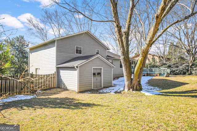 back of property with a wooden deck and a lawn