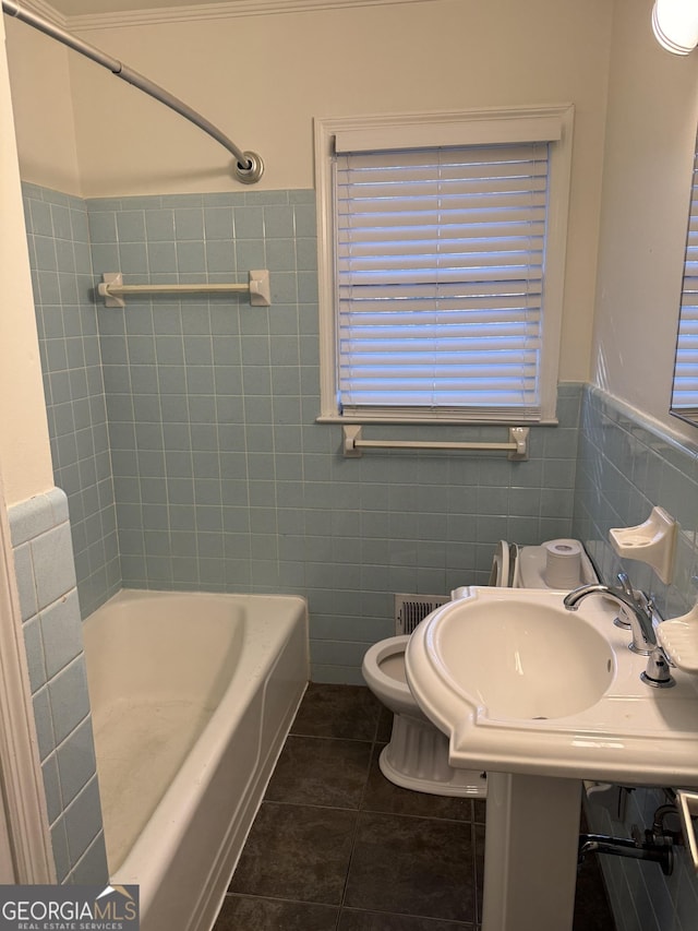 bathroom featuring tile patterned flooring, tile walls, and toilet