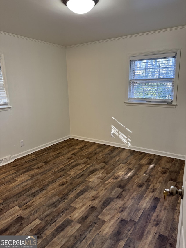 unfurnished room with ornamental molding and dark wood-type flooring