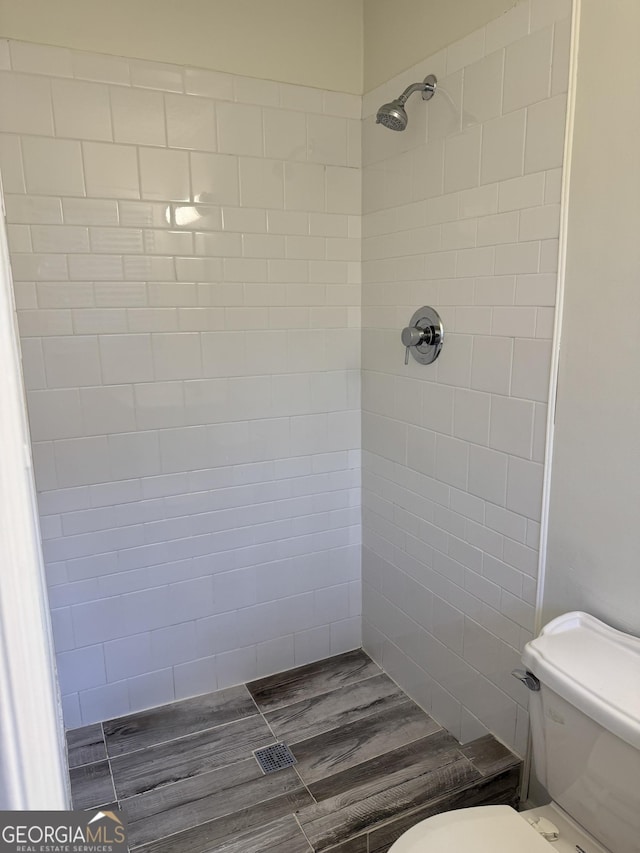 bathroom with toilet and a tile shower