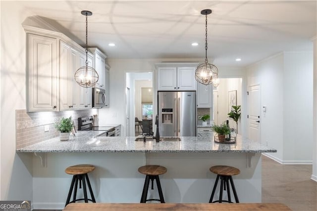 kitchen featuring white cabinetry, light stone countertops, tasteful backsplash, a breakfast bar, and appliances with stainless steel finishes