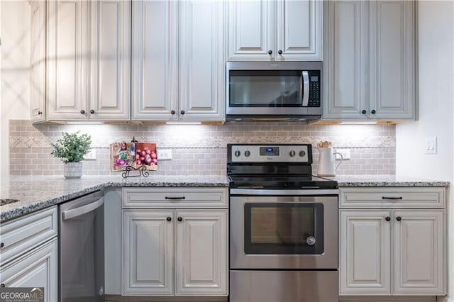 kitchen with decorative backsplash, light stone countertops, white cabinetry, and appliances with stainless steel finishes