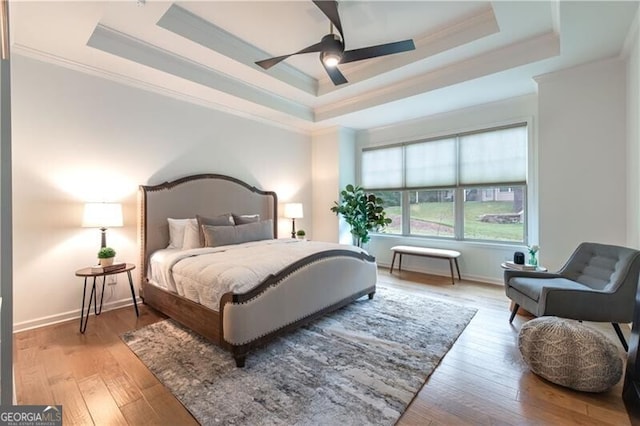 bedroom featuring ceiling fan, ornamental molding, and a tray ceiling