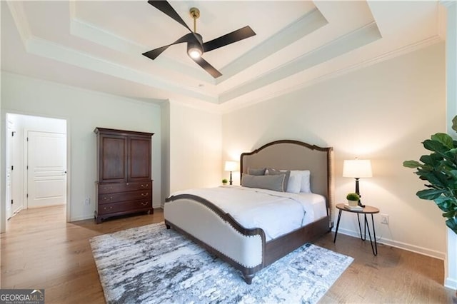 bedroom featuring hardwood / wood-style floors, a raised ceiling, ceiling fan, and ornamental molding