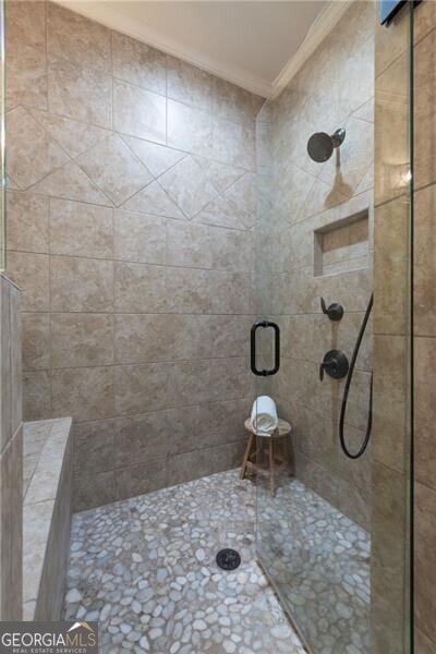 bathroom with a shower with door and ornamental molding