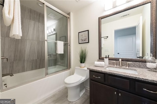 full bathroom featuring combined bath / shower with glass door, wood-type flooring, vanity, and toilet