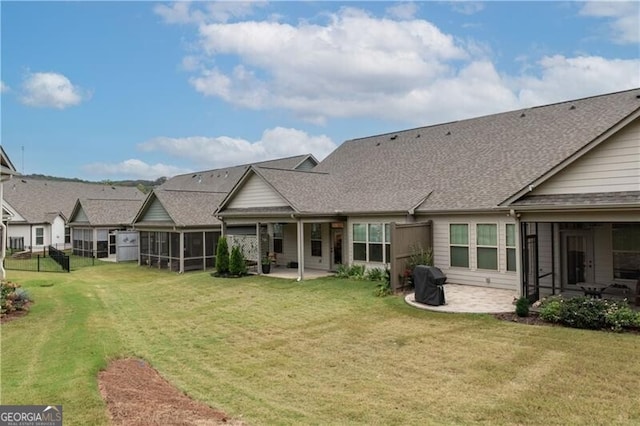 rear view of property with a sunroom, a patio area, and a lawn