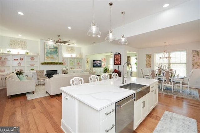 kitchen with dishwasher, sink, decorative light fixtures, a kitchen island with sink, and white cabinets