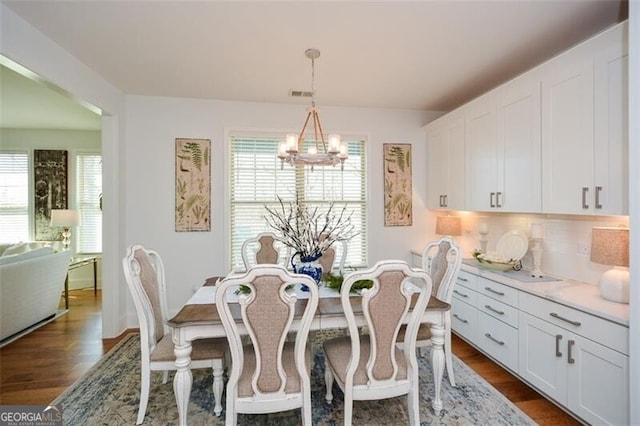 dining space with dark hardwood / wood-style flooring and a notable chandelier