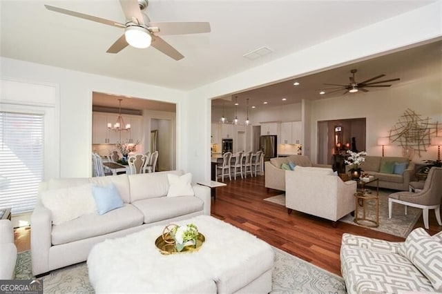 living room with dark hardwood / wood-style floors and ceiling fan with notable chandelier