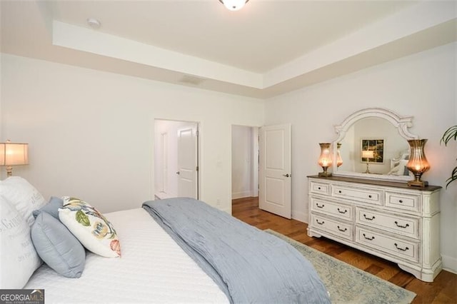 bedroom with a raised ceiling and dark wood-type flooring