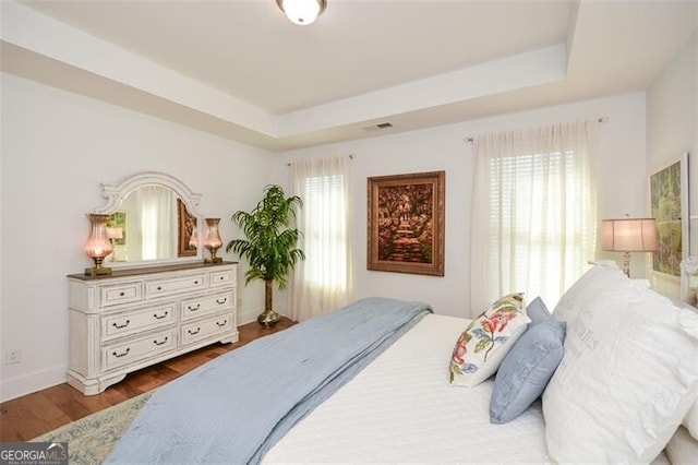 bedroom with a raised ceiling and wood-type flooring