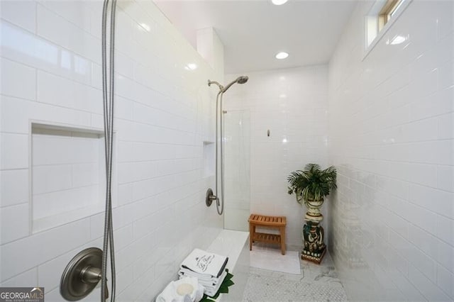 bathroom featuring a tile shower and tile walls