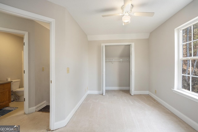 unfurnished bedroom with multiple windows, a closet, light colored carpet, and ceiling fan