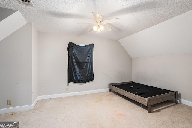 bedroom with vaulted ceiling, ceiling fan, carpet, and a textured ceiling